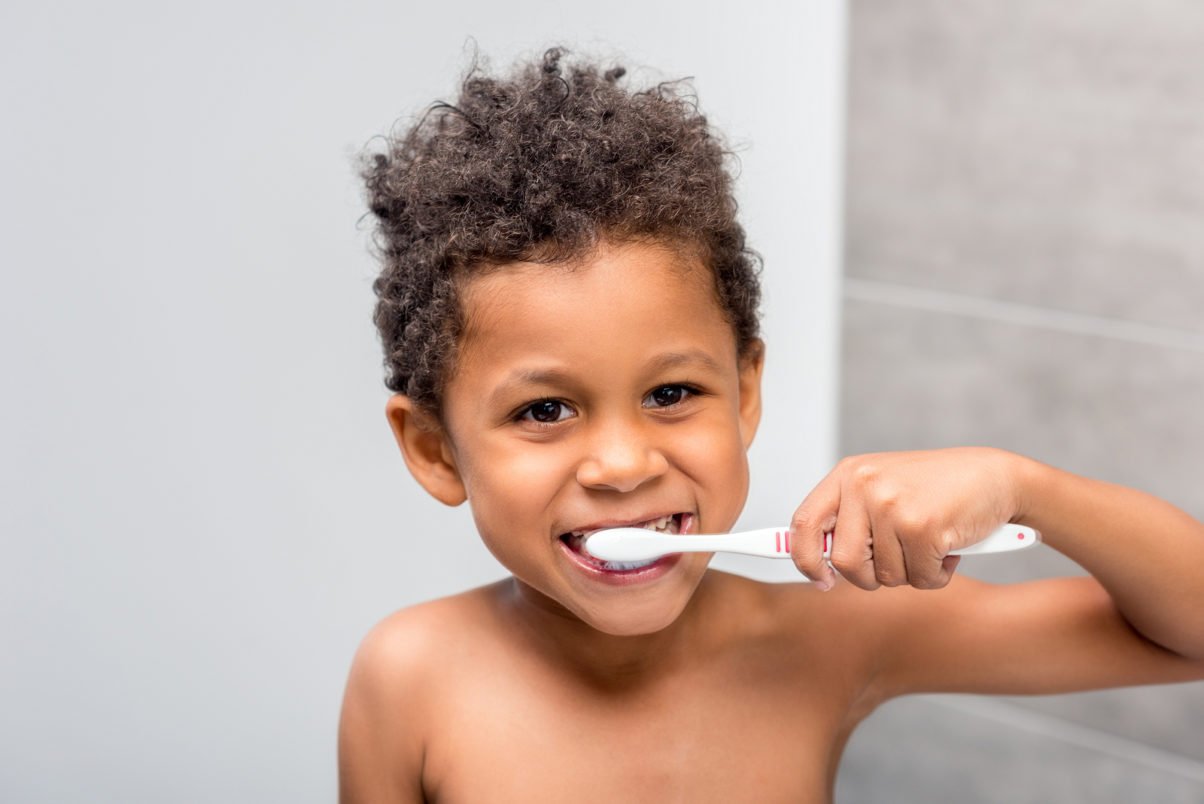 close-up portrait of happy african-american kid brushing teeth