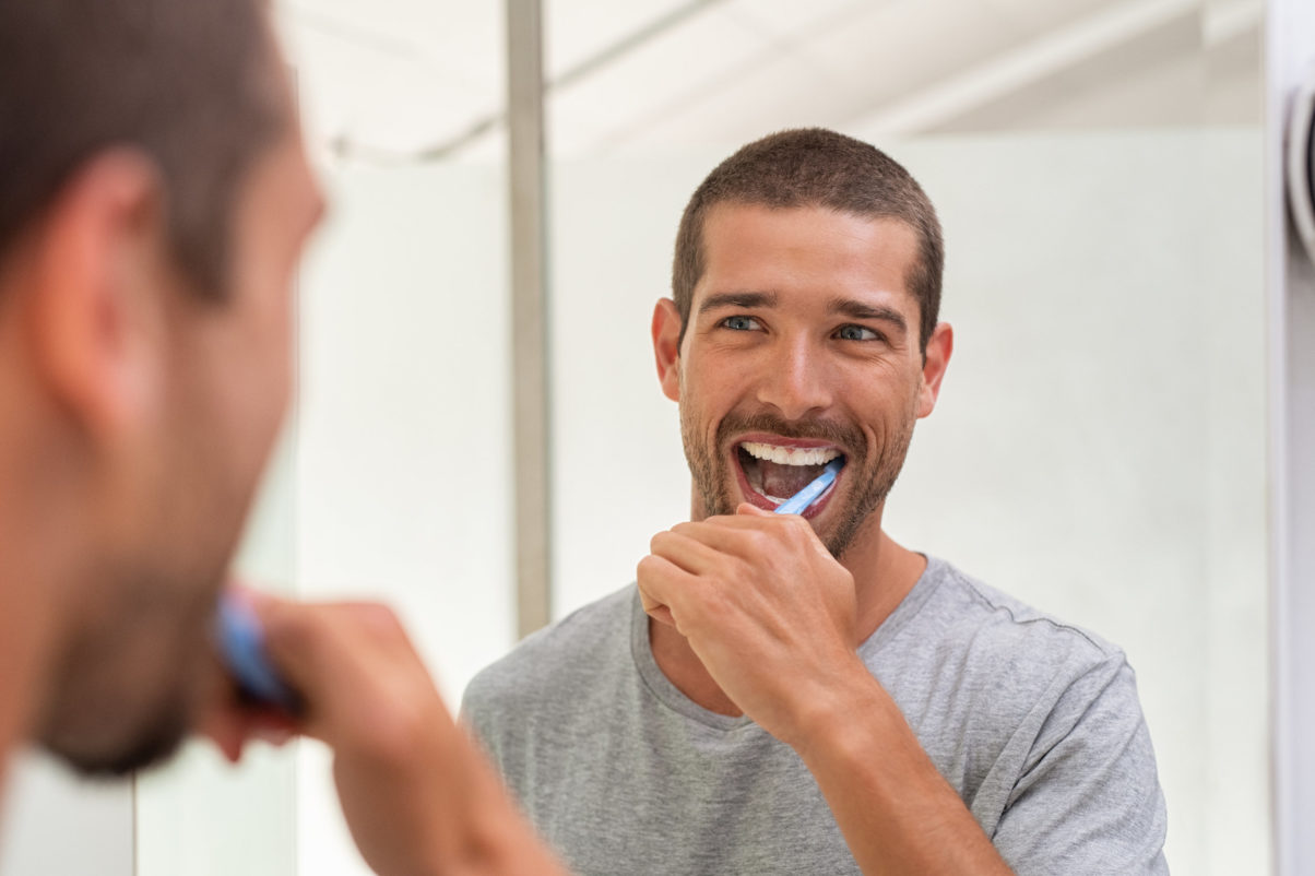 Man brushing his teeth in the mirror