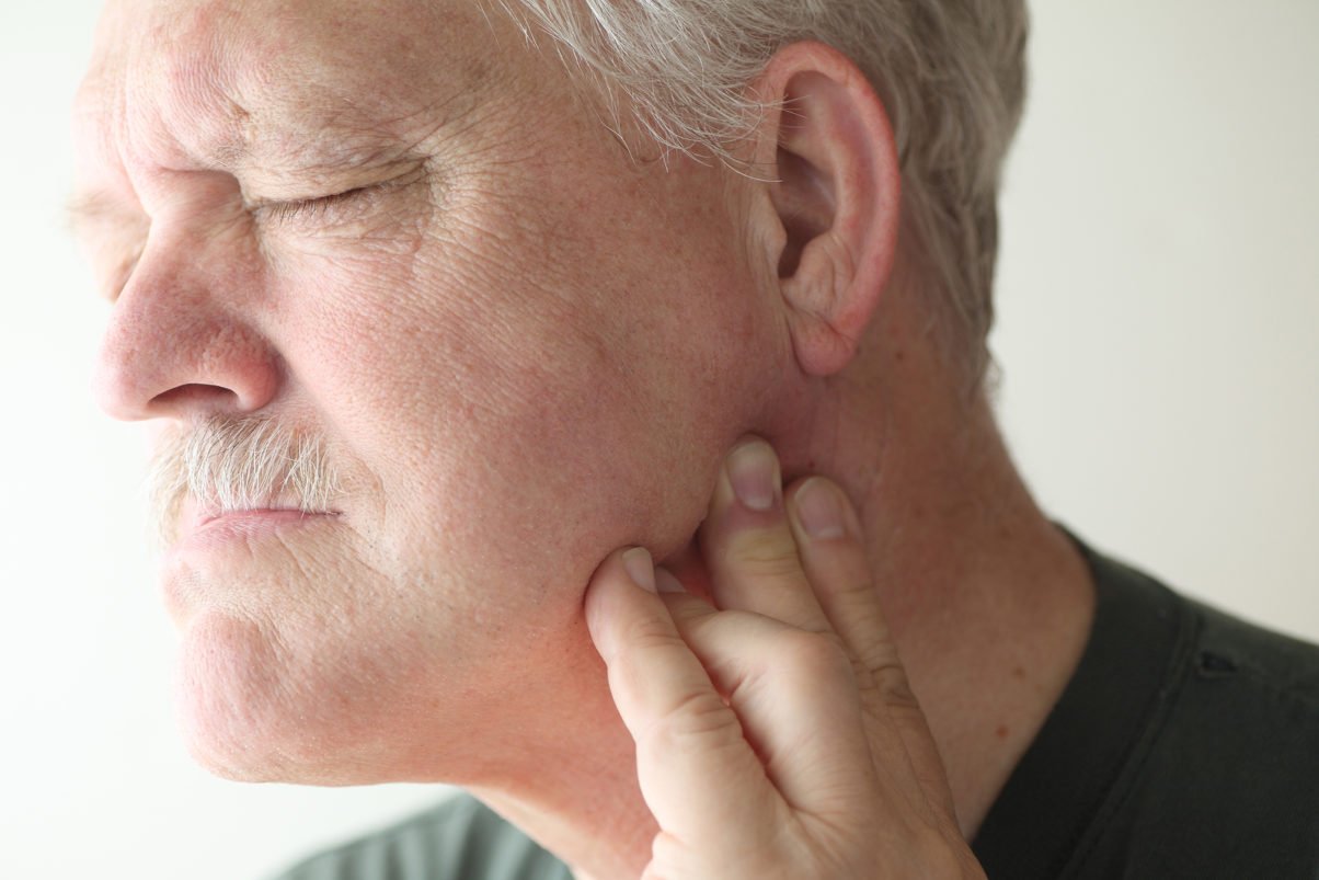 senior man suffering from pain in his jaw (TMJ)