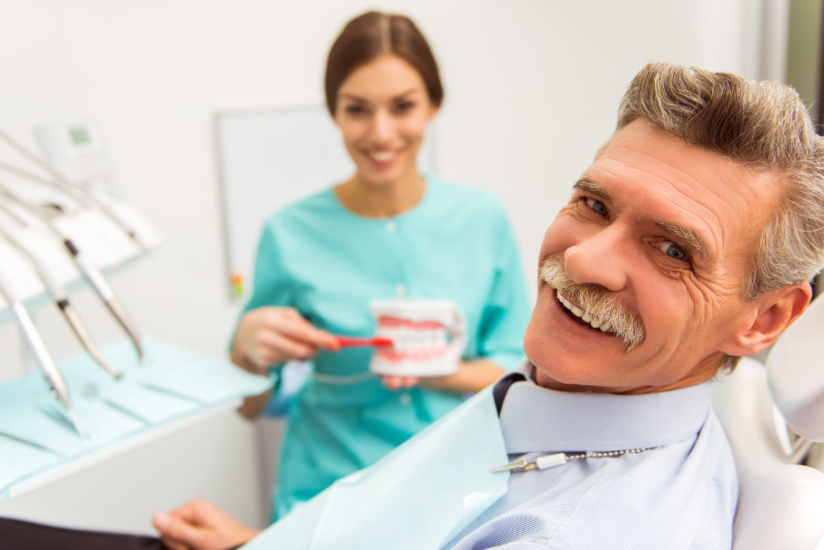 Man in dental chair smiling next to dentist