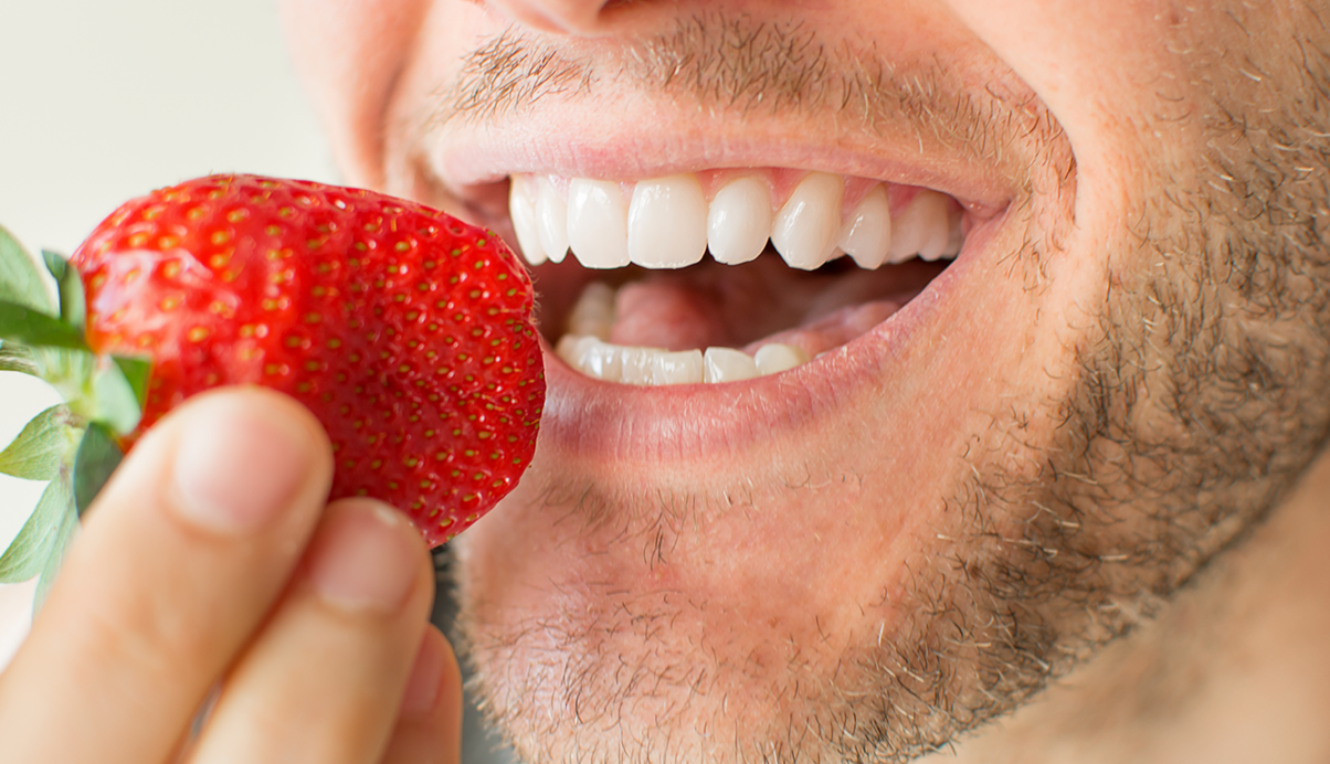 man about to bite into a strawberry