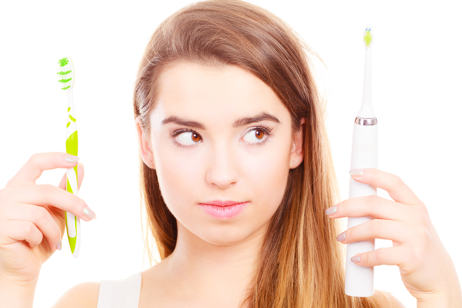 Woman holding choosing between electric and traditional toothbrush have to make decision what is best for teeth.