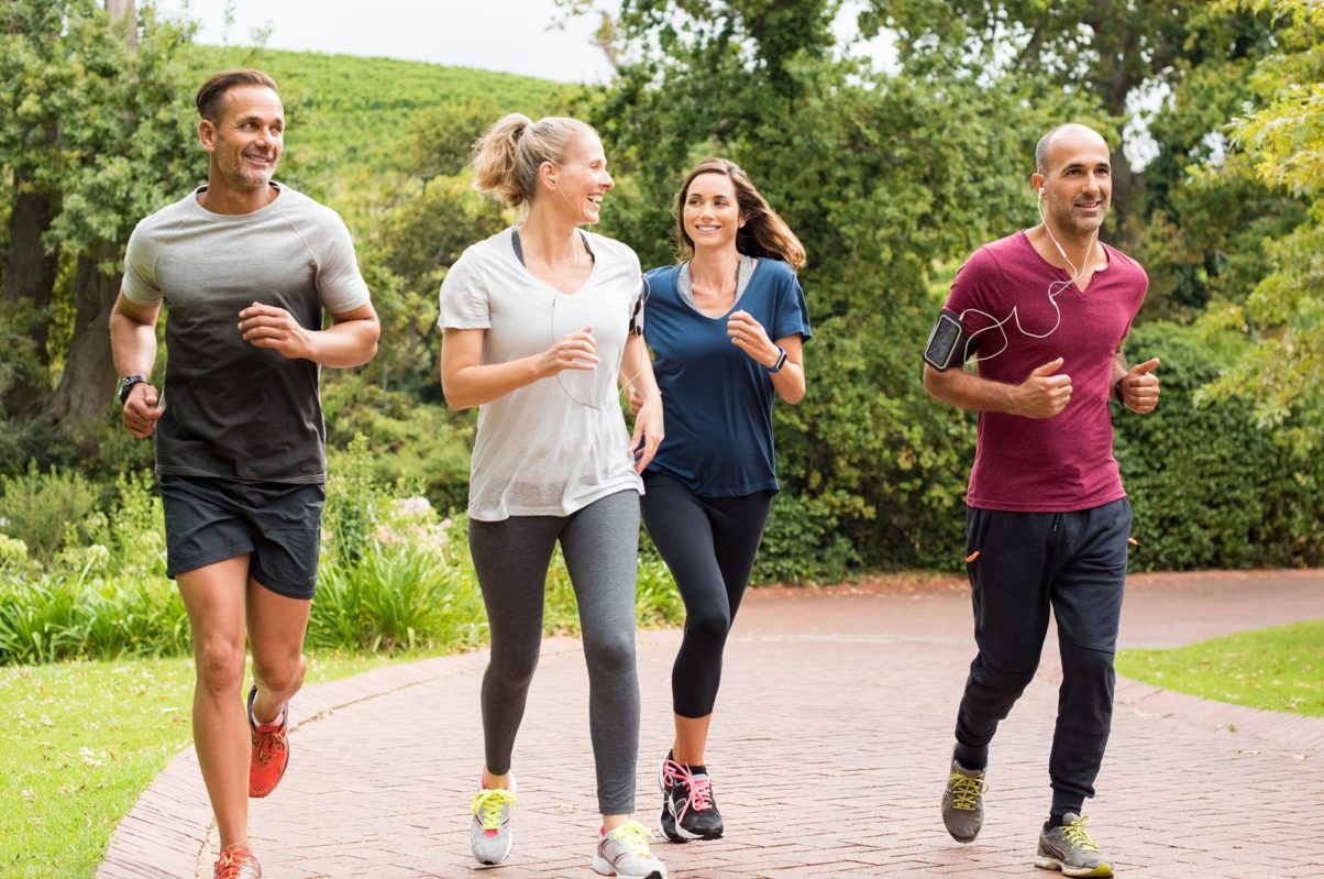 Healthy group of people jogging on track in park.