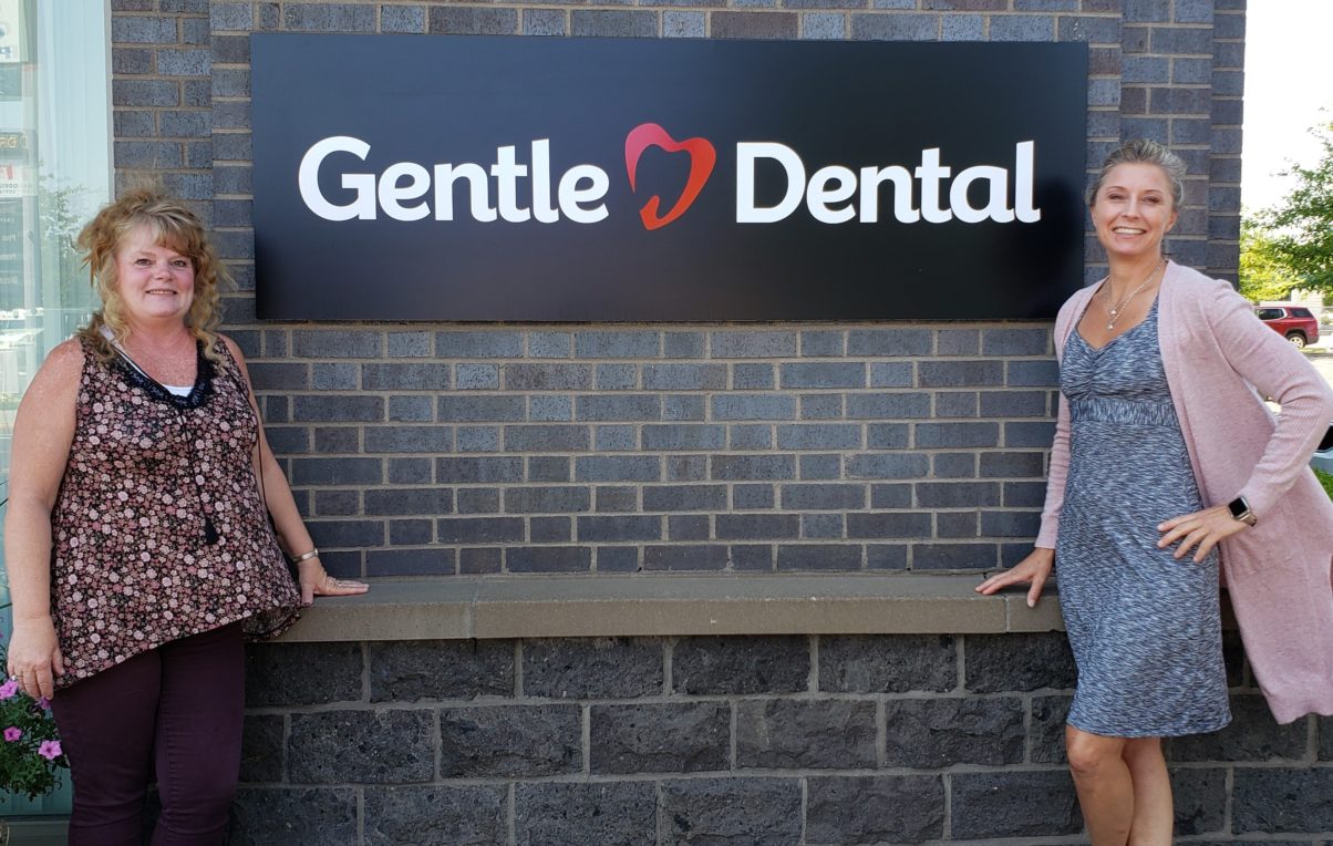 Gentle Dental staff smiling in front of the office sign in Madras, Oregon